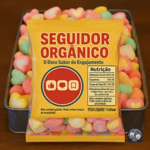Uma embalagem amarela vibrante de um doce imaginário chamado "SEGUIDOR ORGÂNICO - O Doce Sabor do Engajamento" em close-up, sobre um fundo desfocado de marshmallows coloridos. A embalagem exibe um círculo vermelho com os ícones brancos de "Curtir", "Comentar" e "Salvar" do Instagram. Abaixo, uma tabela de "Nutrição" lista "Validação Social 100% VD", "Dopamina 75% VD", "Tempo de Vida Útil 15% VD" e "Relevância (Alimento para o Algoritmo) Valor Diário não estabelecido". Há também os dizeres "Não contém glúten. Pode conter traços de ansiedade." repetidos na parte inferior da frente e no verso da embalagem, e "PESO LÍQUIDO 1 Follow" no canto inferior direito.